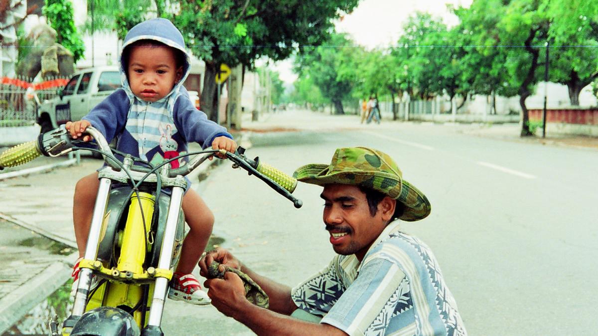 Man holding his kid on a bike.