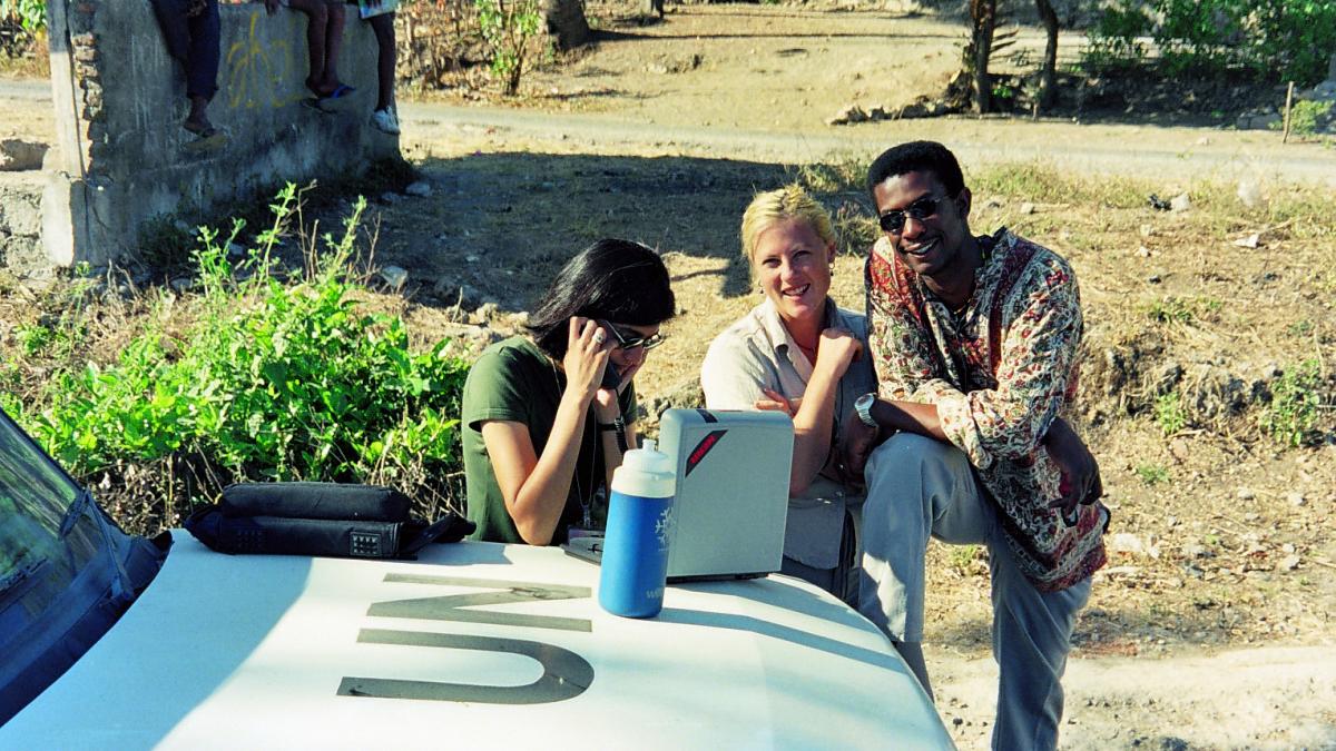 Three people sitting next to each other outside.